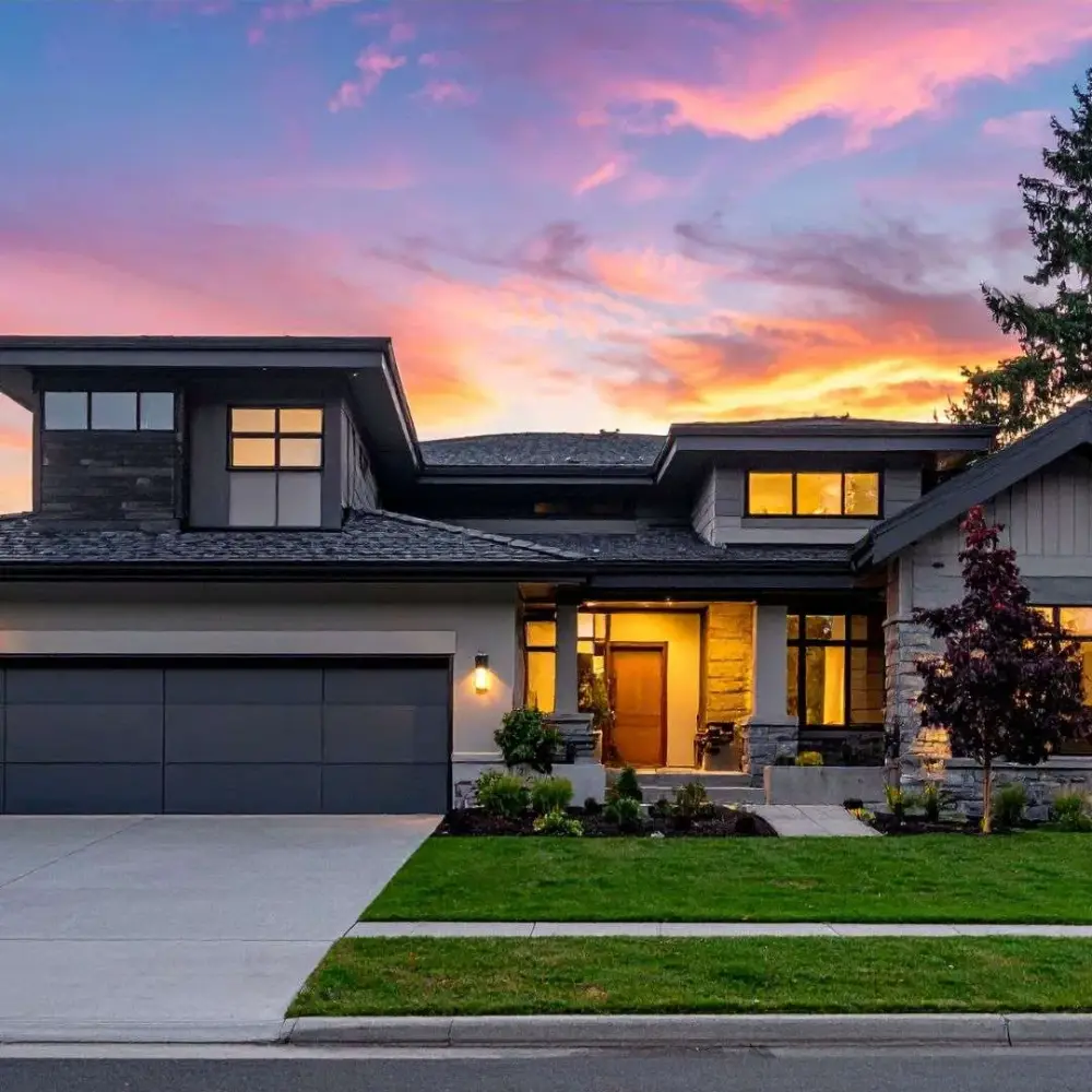 A modern detached home lit up at dusk